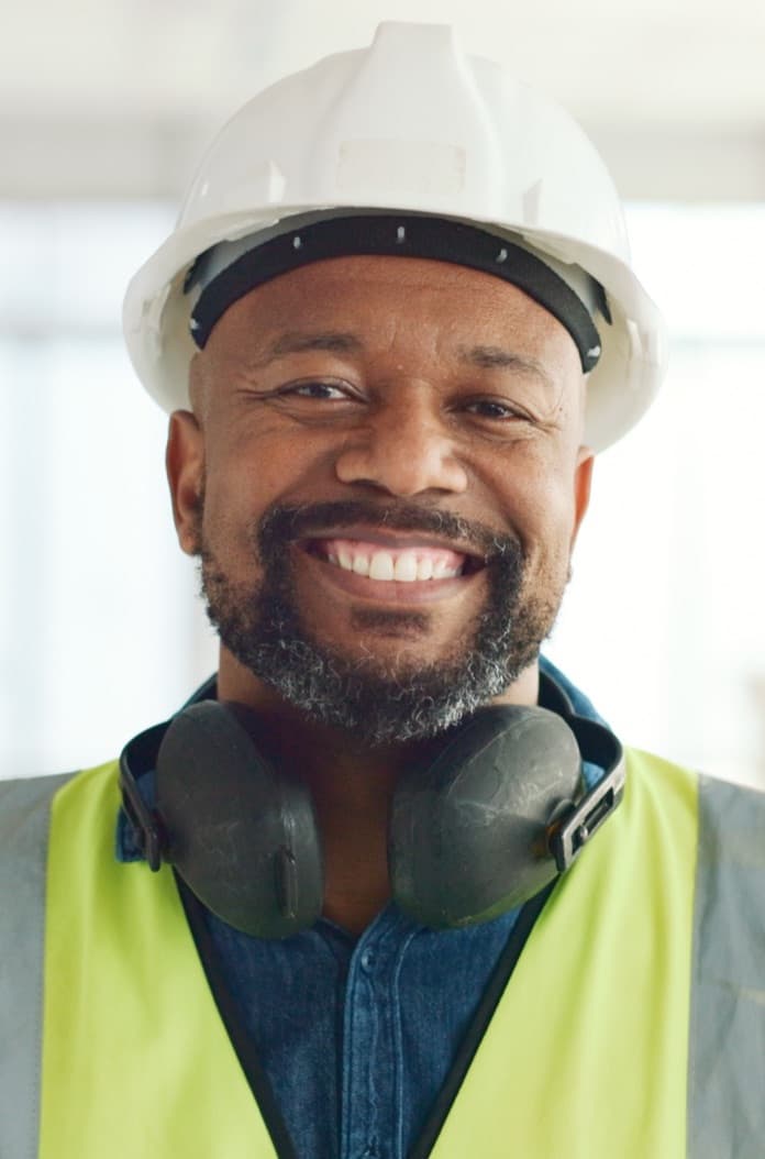 Smiling construction worker with ear defenders around his neck