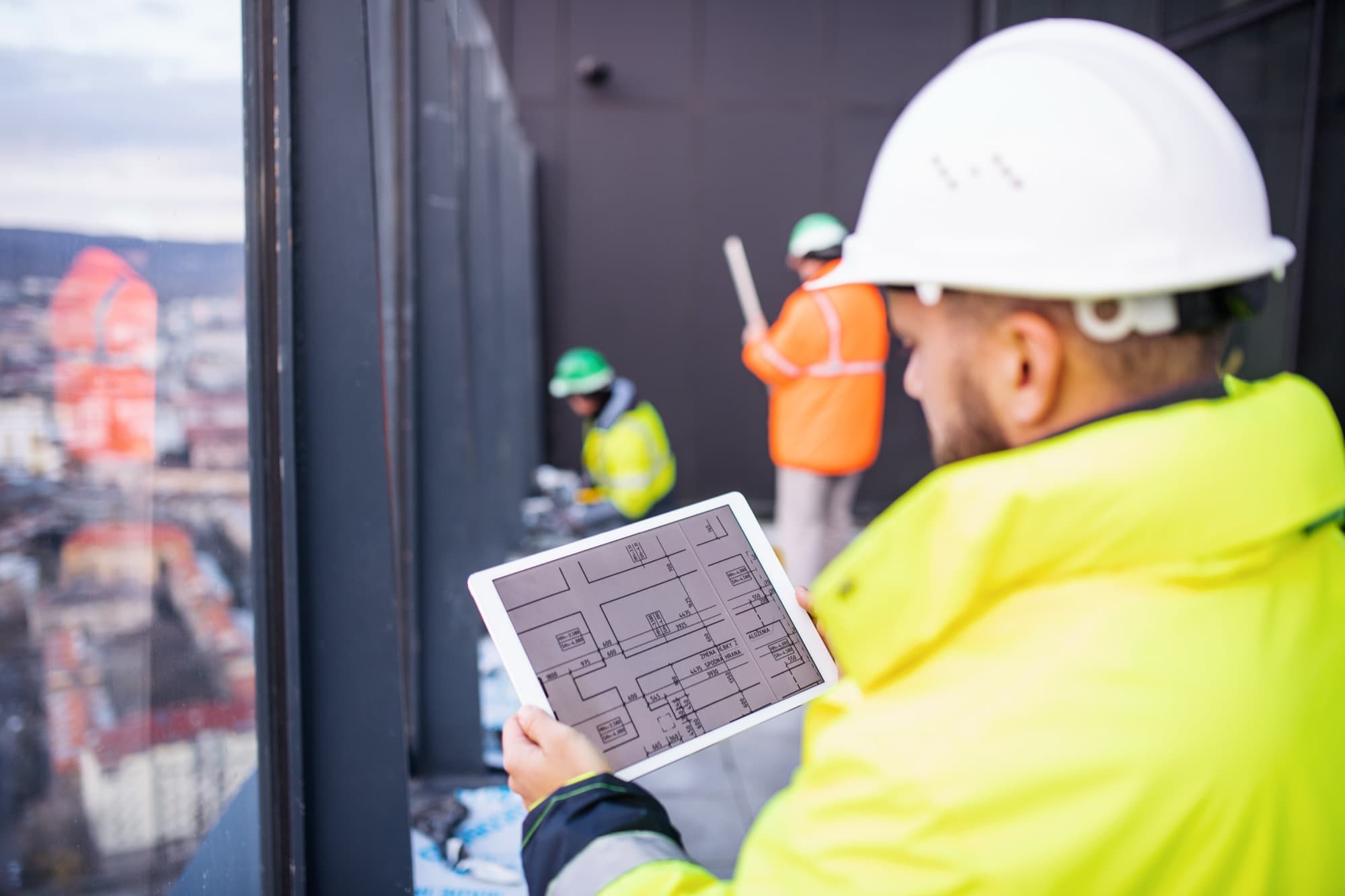 Site worker reviewing plans and a tablet on a construction site