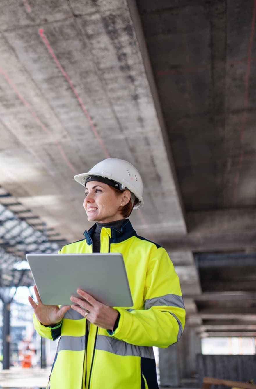 Engineer recording a site inspection on a tablet beneath a concrete slab