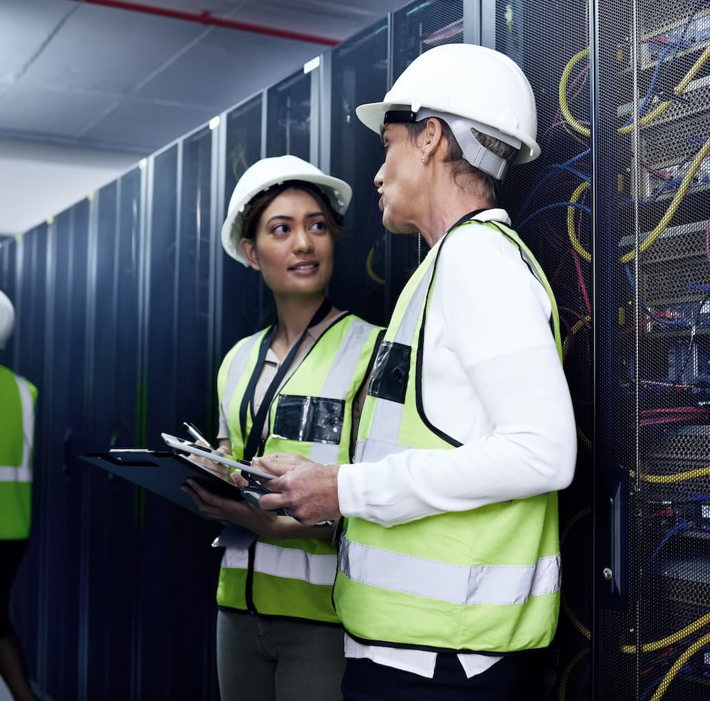 Engineers recording commissioning and QA/QC inspections in a data center server room